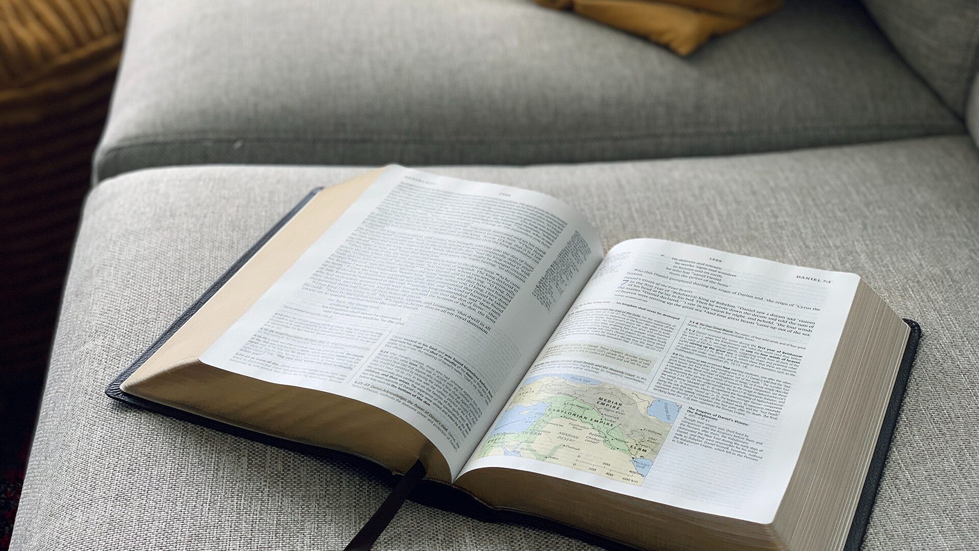open Bible on top of a gray sofa