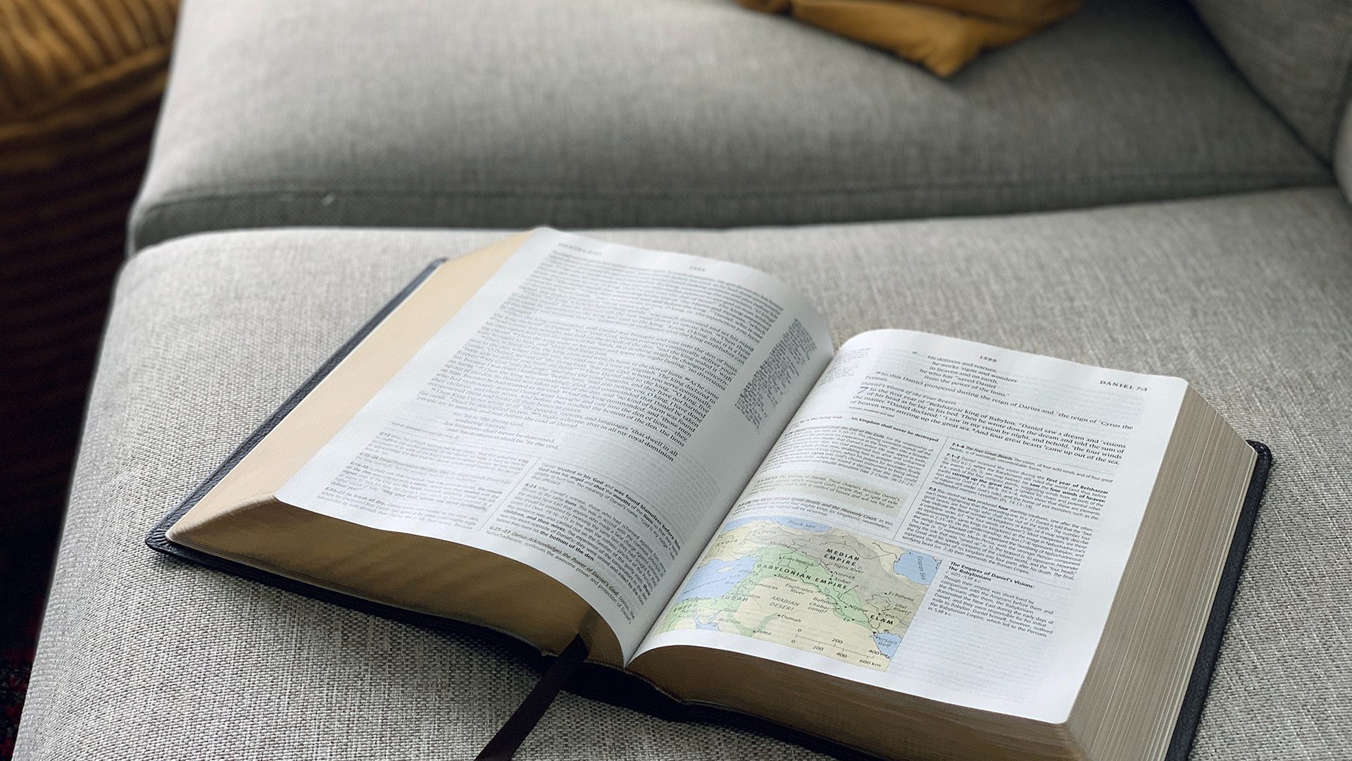 open Bible on top of a gray sofa