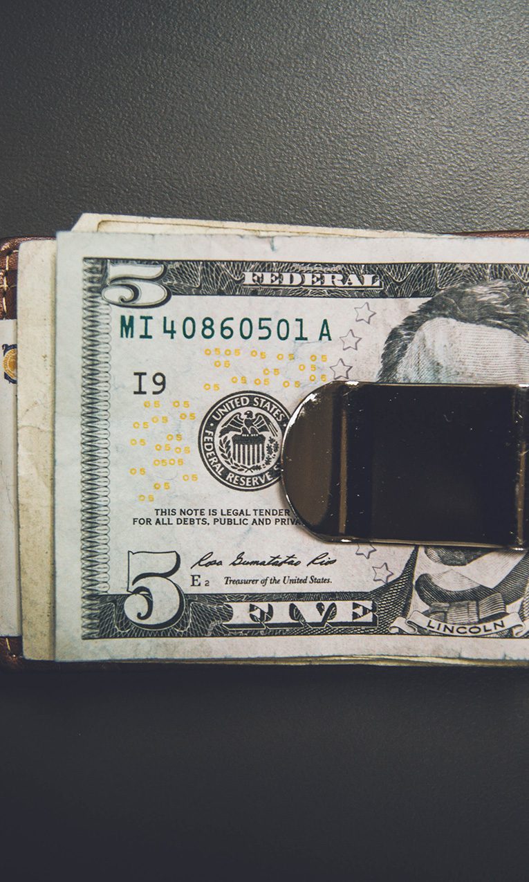 clip wallet holding several US dollar bills