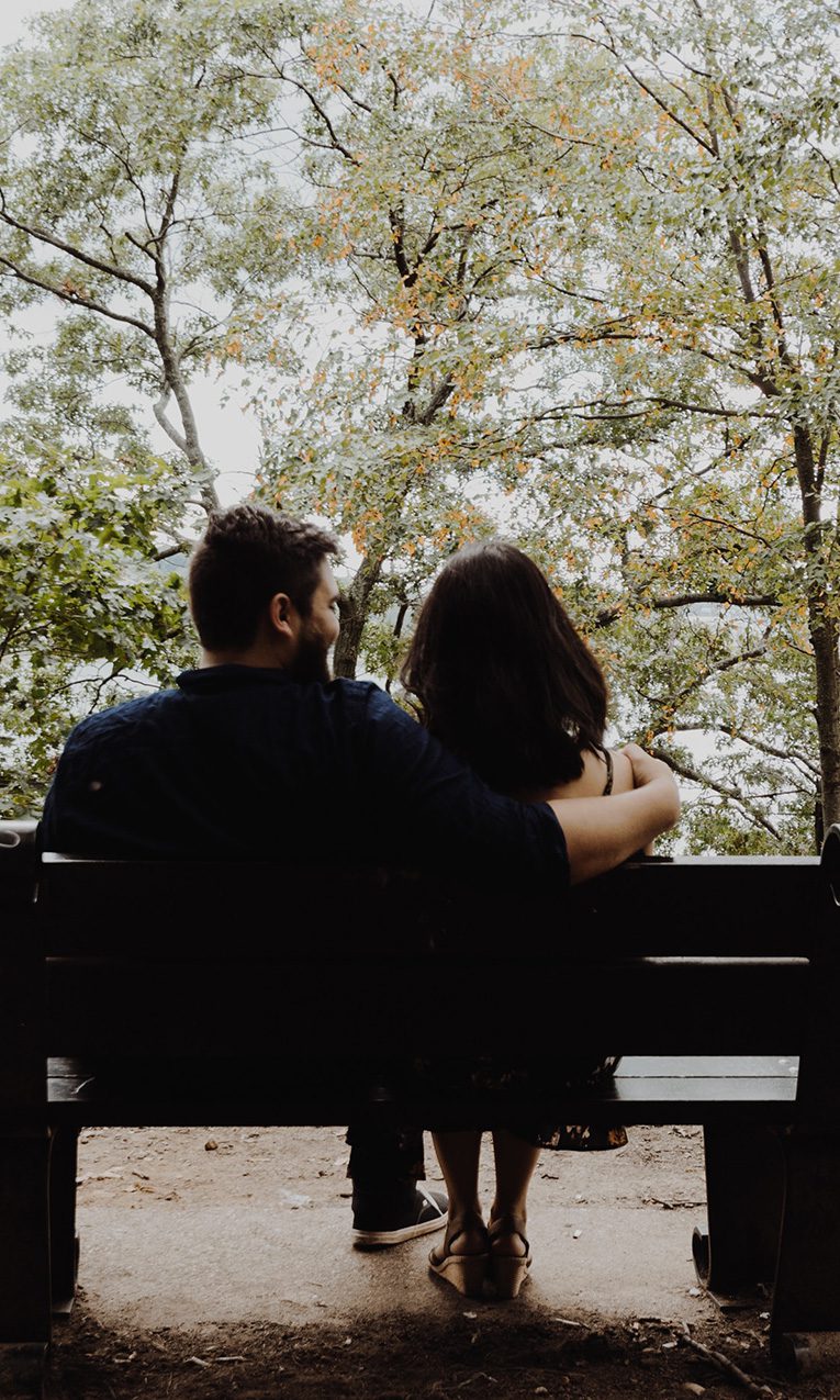 Man hugging his wife while sitting on a wooden bench