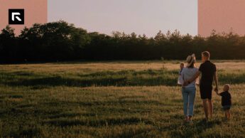 A mother holding her baby with her husband's arm wrapped around her and his hand holding a little boy in a field