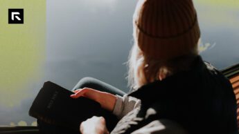 A girl sitting in a hammock with a beanie on and her Bible in her lap