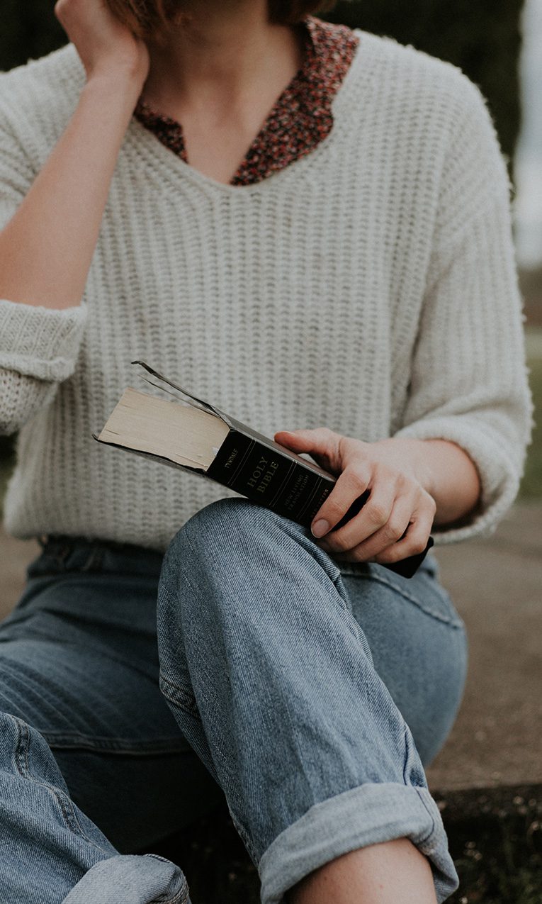 young woman sitting on outdoor steps holding a Bible