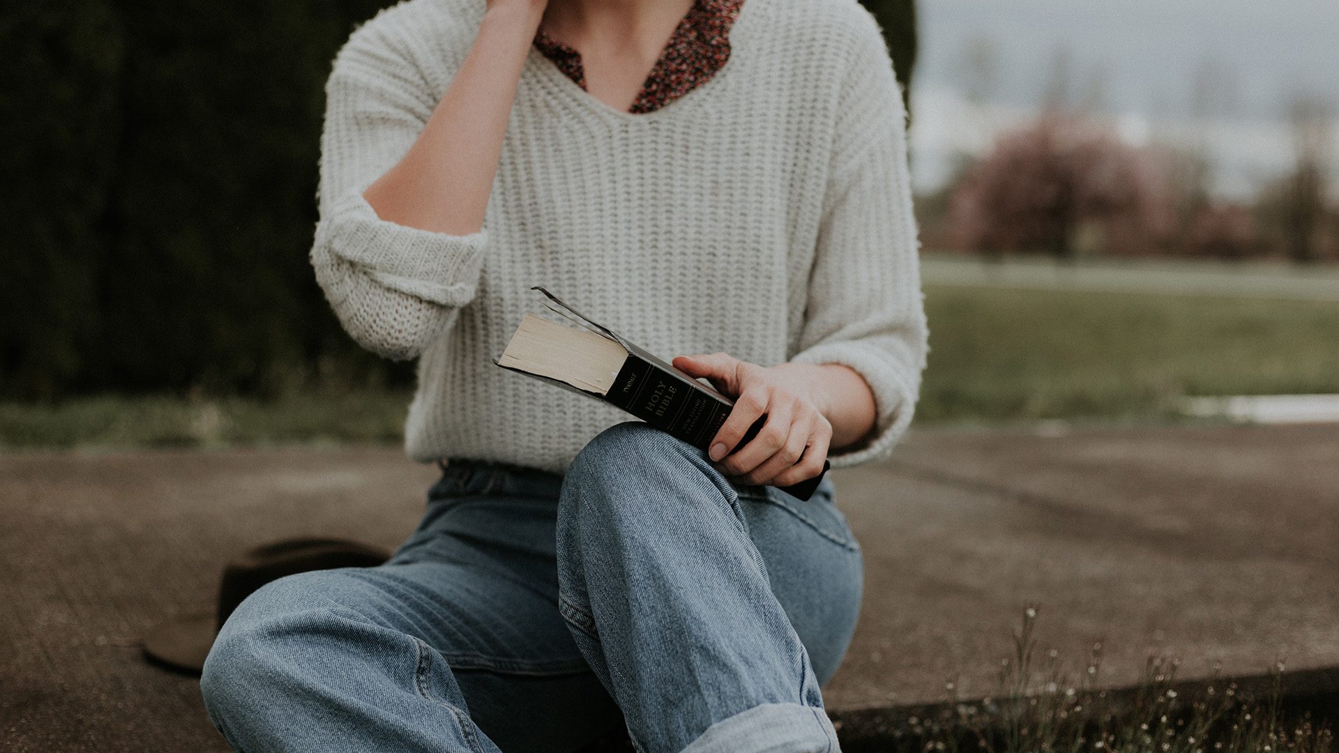 young woman sitting on outdoor steps holding a Bible