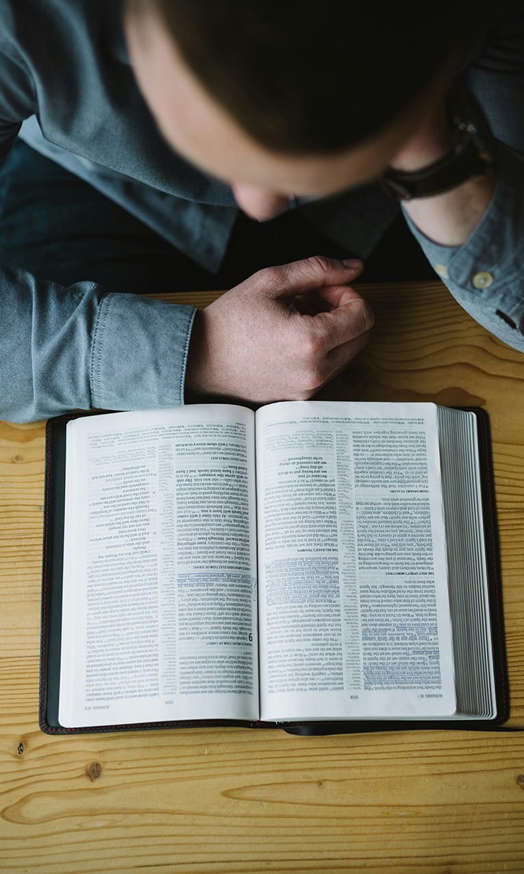 a man reading his Bible along with the book Expositional Preaching from 9marks