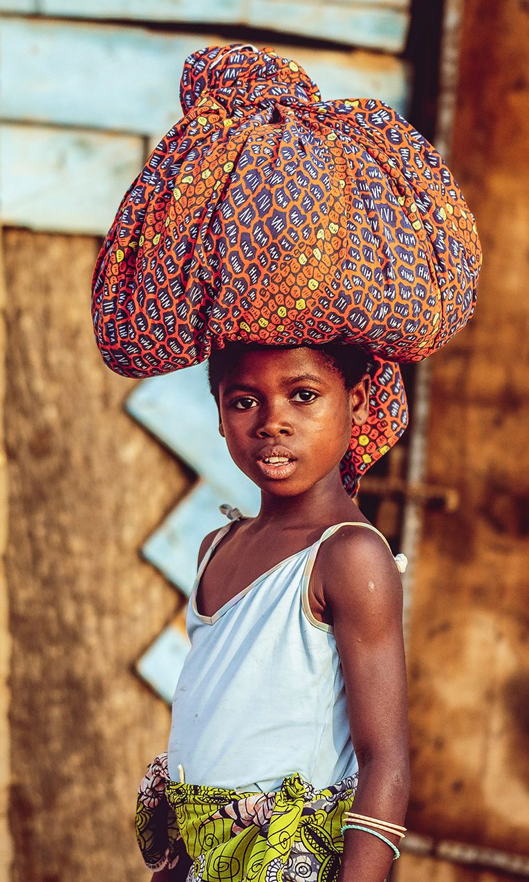 Young African child, carrying a large sack on her head, and the ivory coast of West Africa.