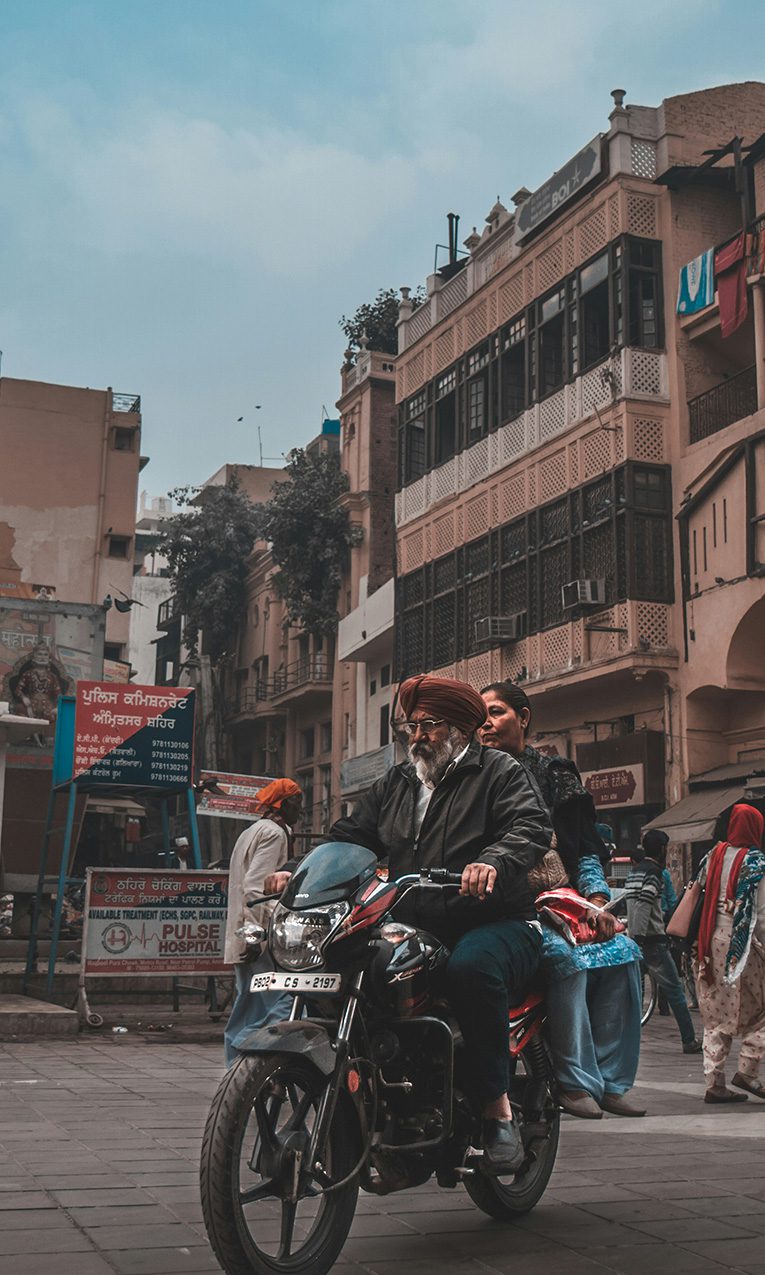 man and woman riding a motorcylce on a busy street of India