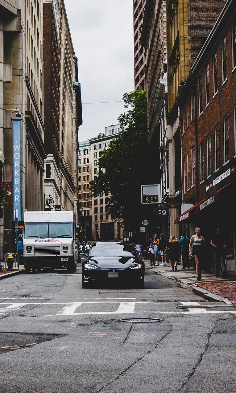 cars parked on side of the road in between buildings during daytime