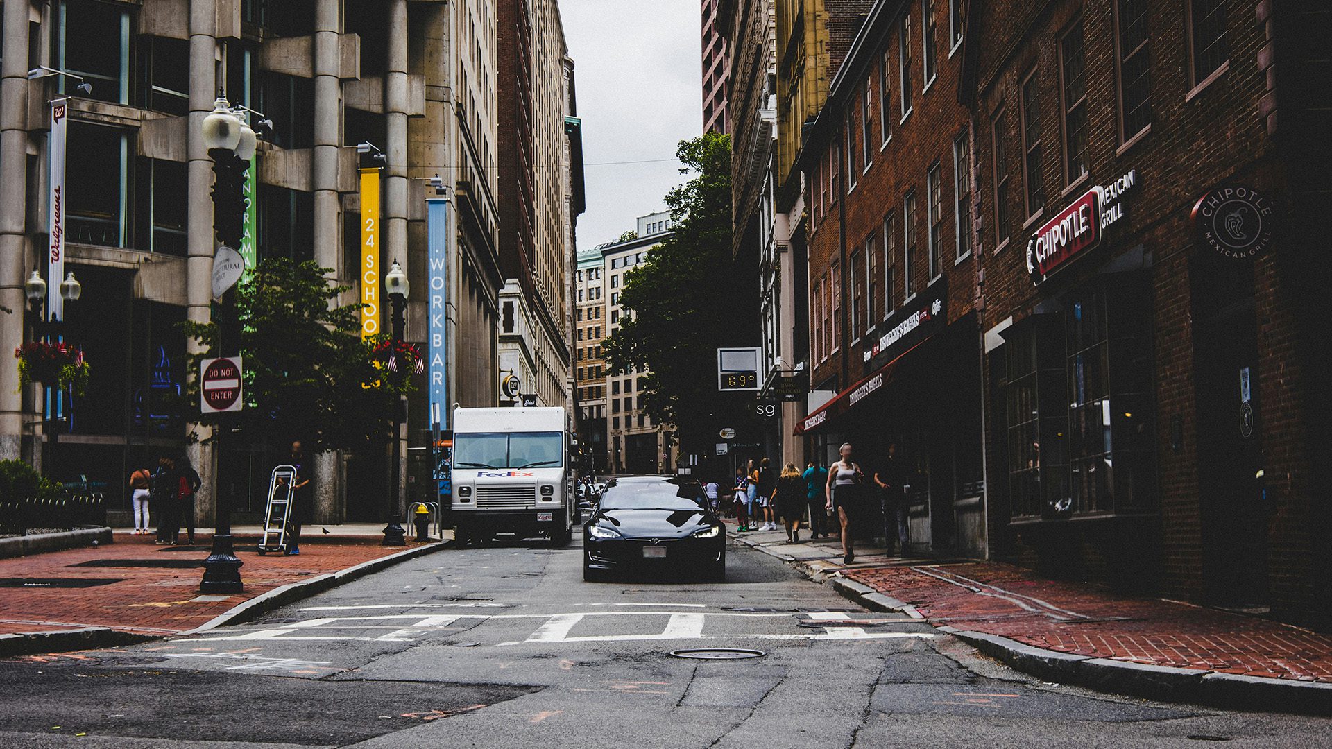 cars parked on side of the road in between buildings during daytime