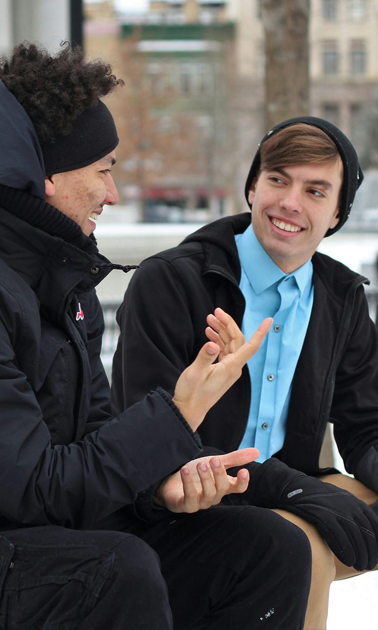 two men talking while sitting on a bench