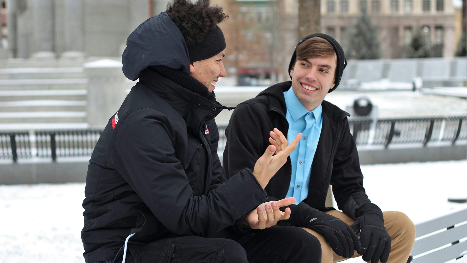 two men talking while sitting on a bench