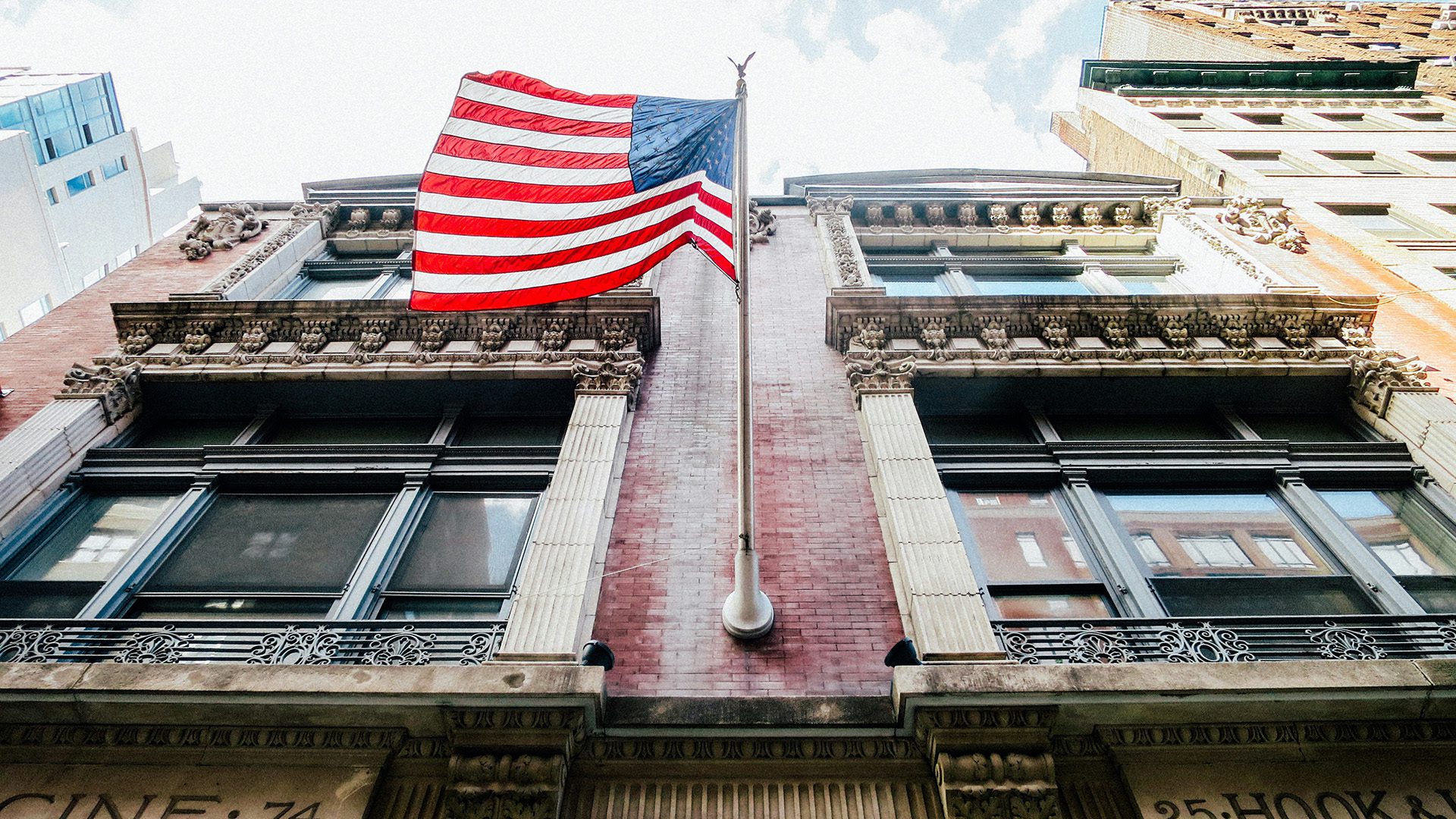 an United States flag hanging from a pole on a building