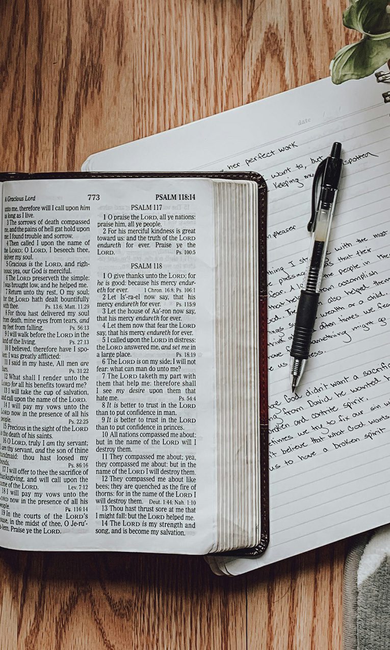 an open Bible, a notebook, and a pen