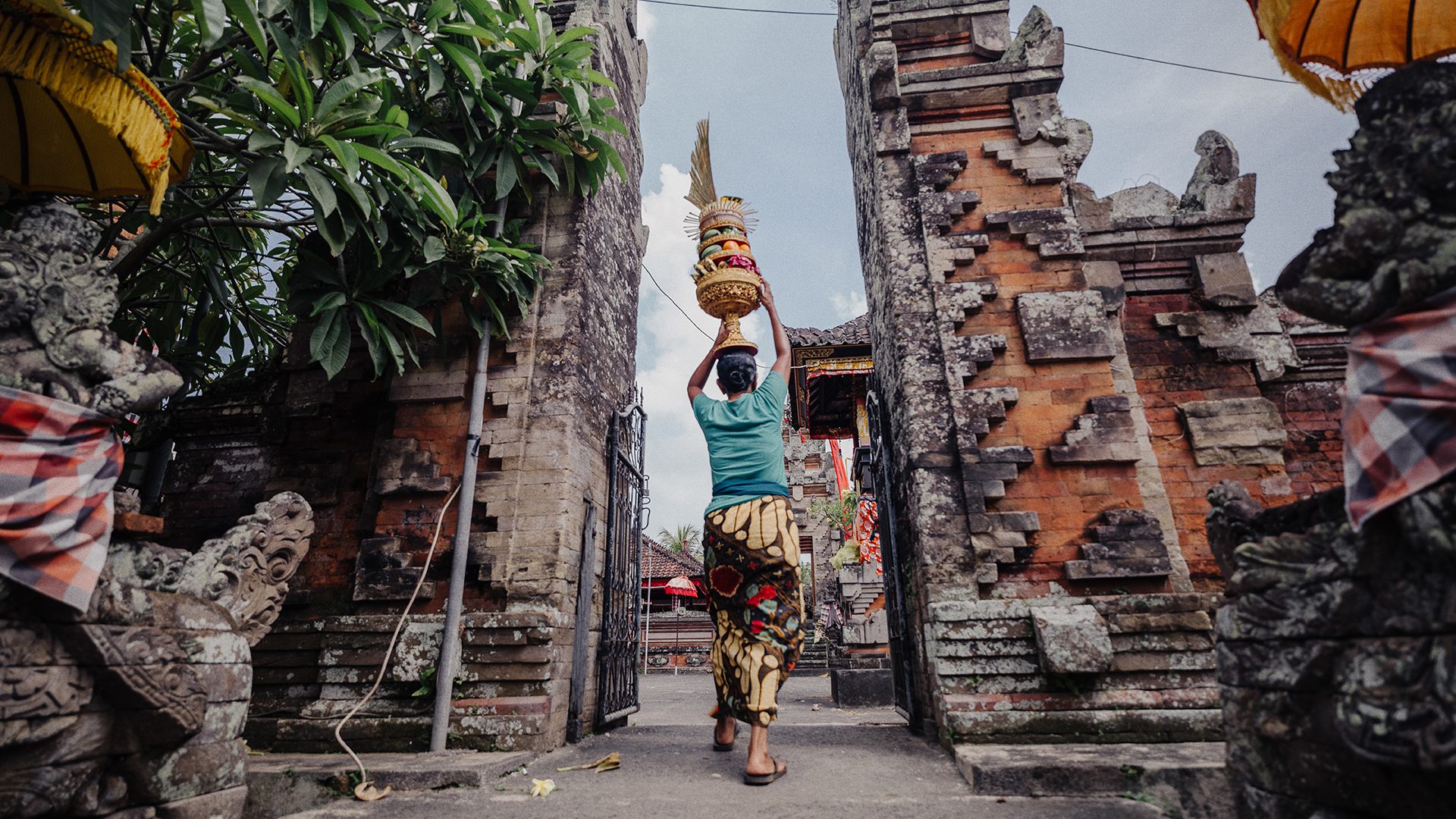 A woman walking through temple grounds in Indonesia.