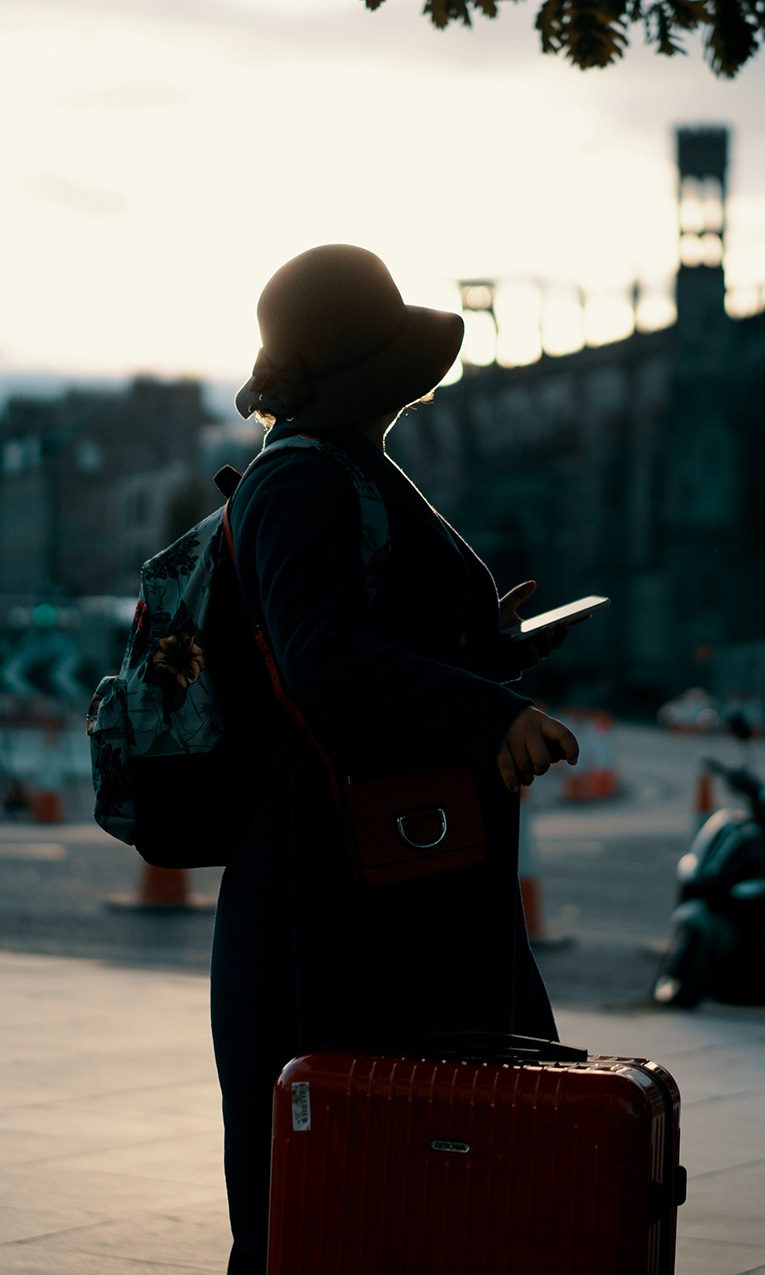 A woman pulling her luggage on the sidewalk.