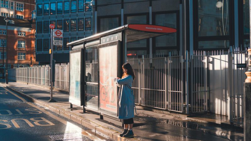 A woman stading at a bus stop.
