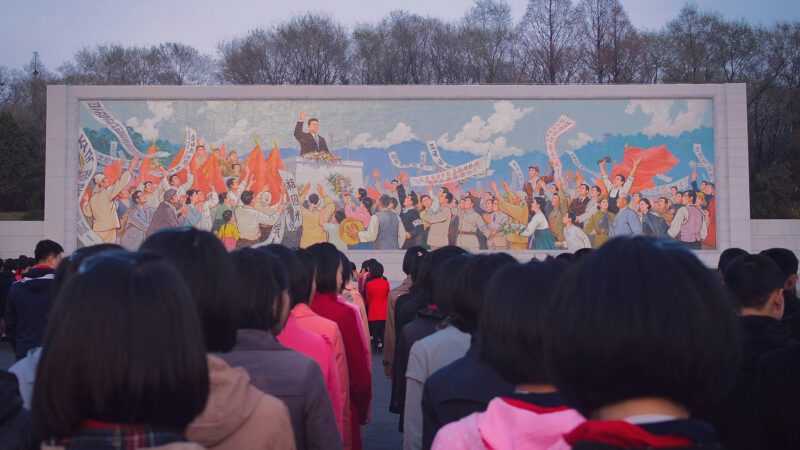 Children line up in front of government propaganda in North Korea.