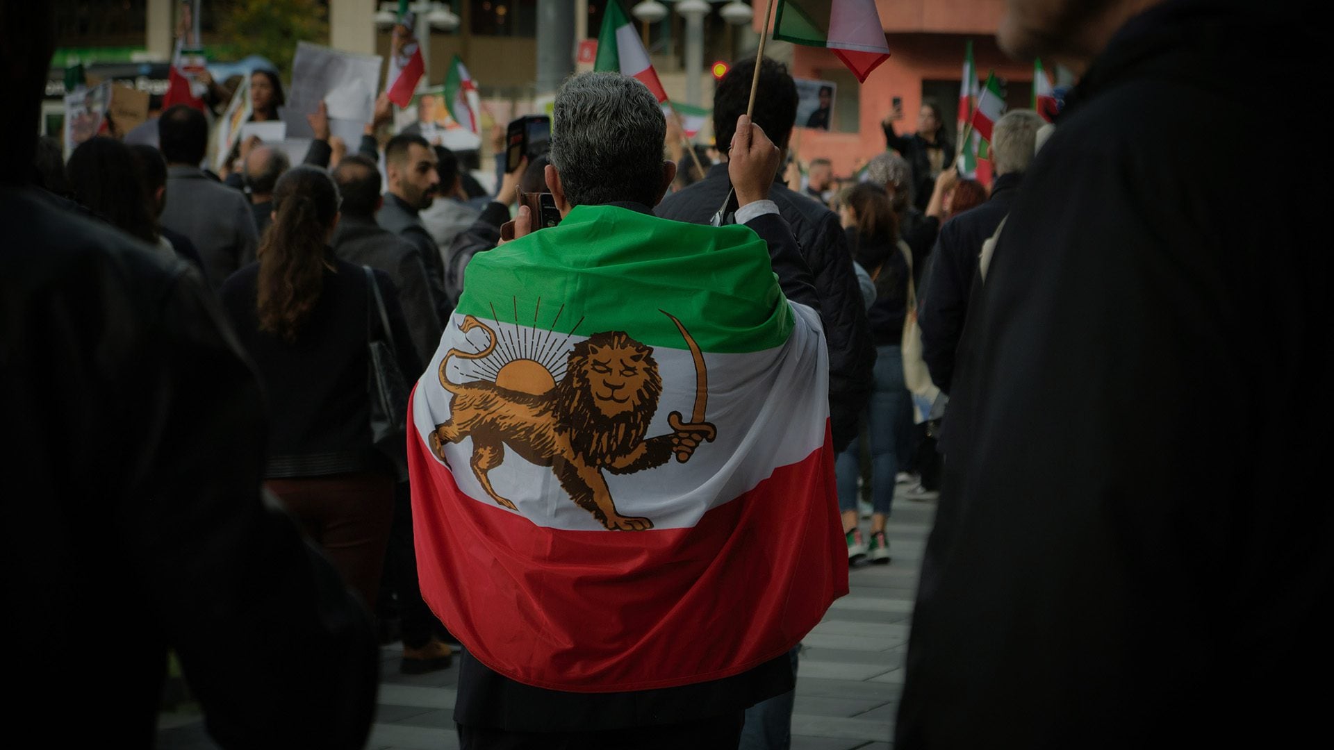 A man wearing an Iranian flag at a protest.