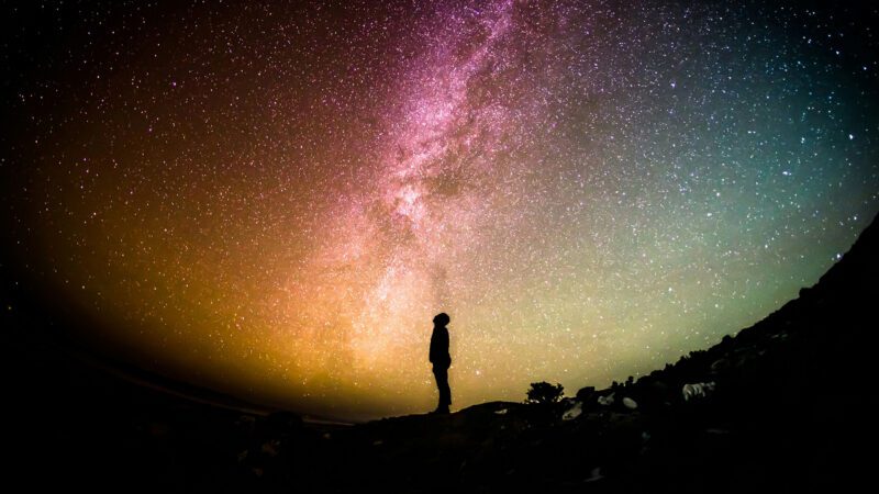 Silhouette of a man standing under the aurora borealis.