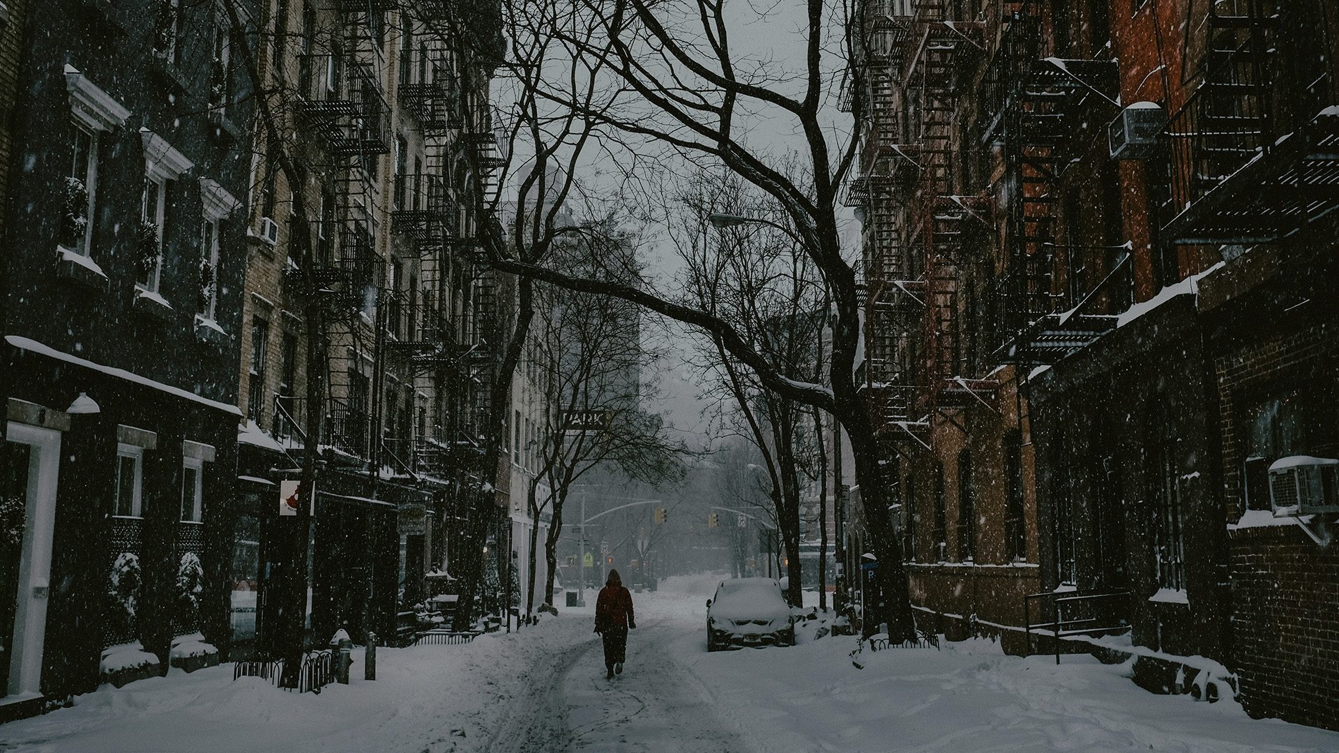 A man walking through a street filled with snow.