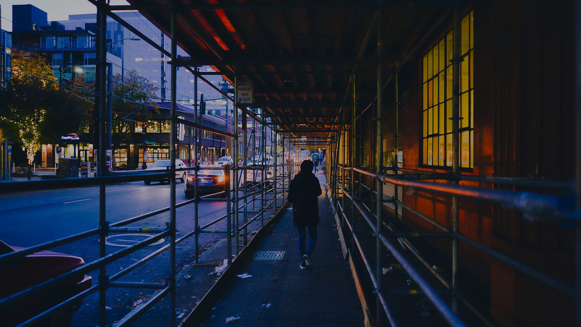A woman walking on the sidewalk of a busy street.