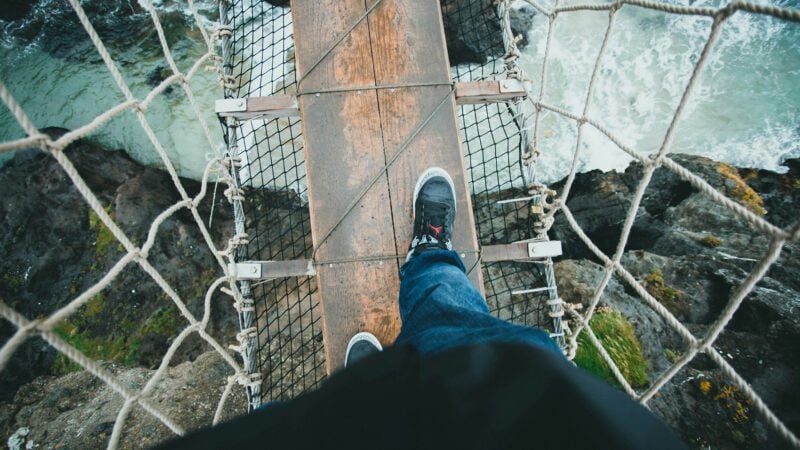 A man walking on a suspension bridge.