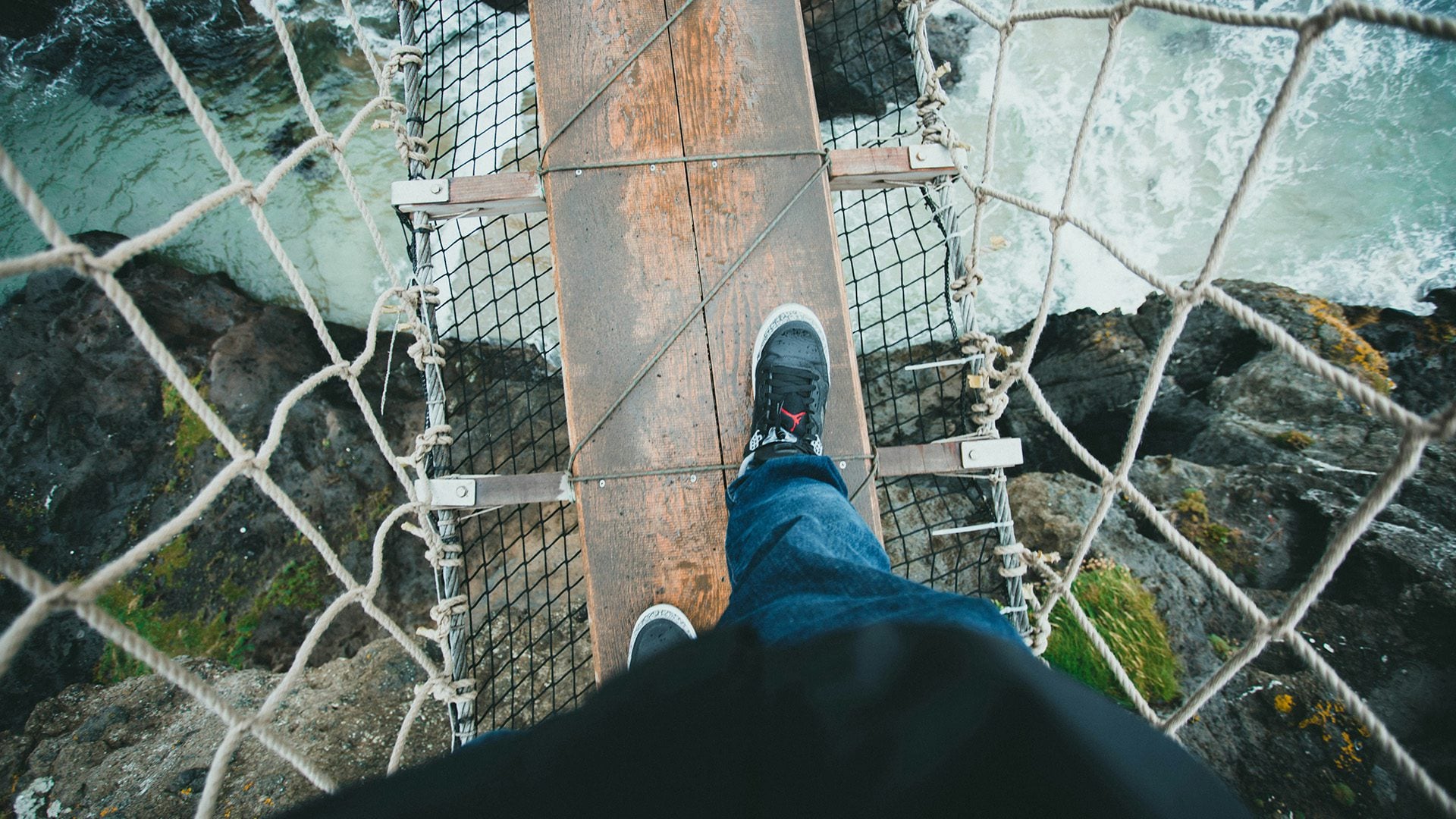 A man walking on a suspension bridge.