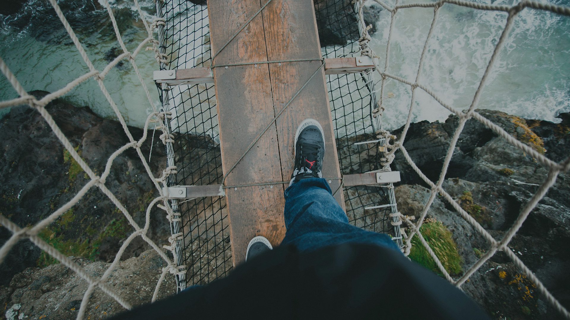 A man walking on a suspension bridge.