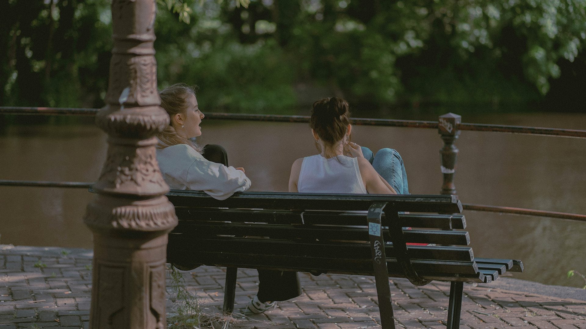 Two girls talking on a bench.
