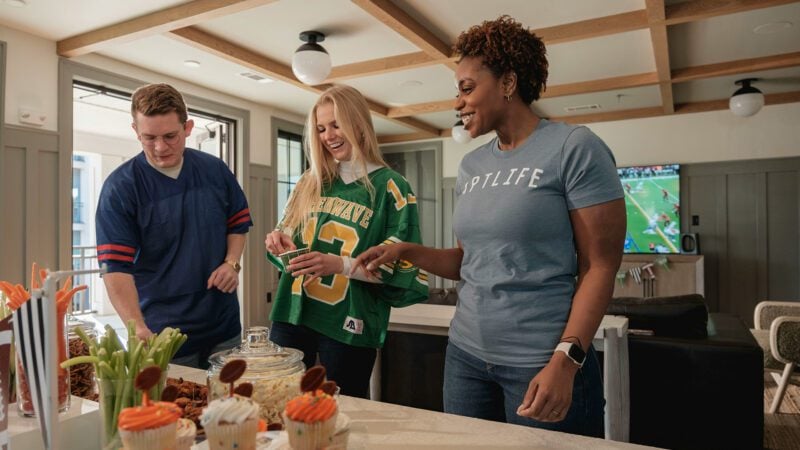 Three friends gathered around a table with snacks.