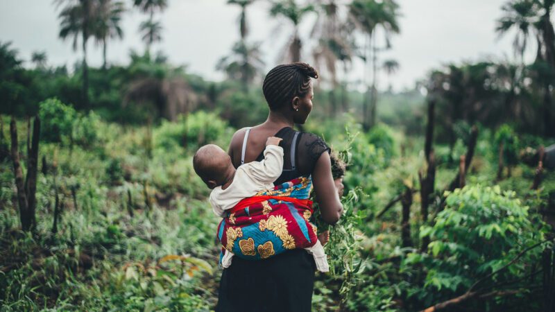Mother and child walking through tropical forest.