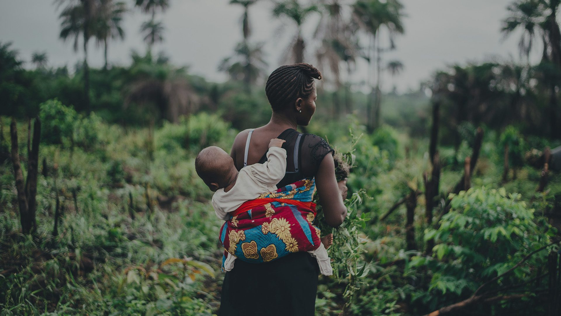 Mother and child walking through tropical forest.