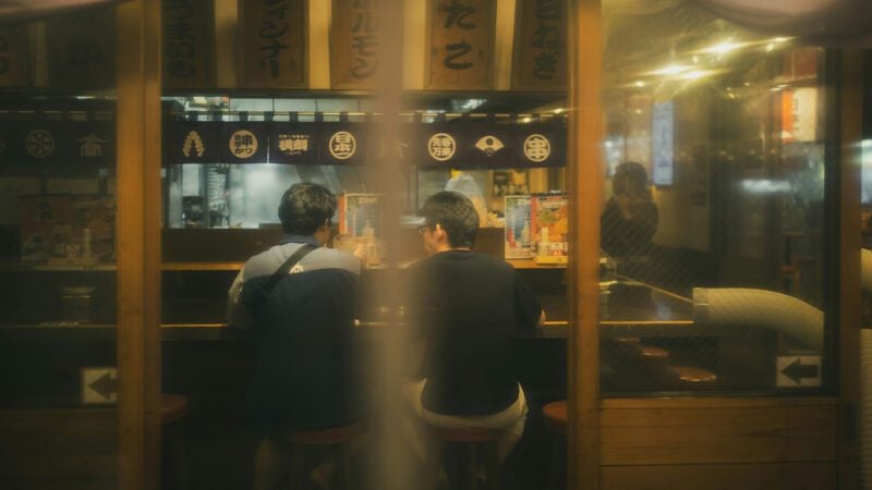 Two people sitting at a counter in a restaurant.